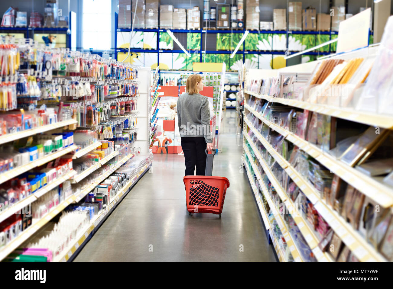 Frau mit einem Korb auf Rädern in einem SB-Warenhaus. Stockfoto