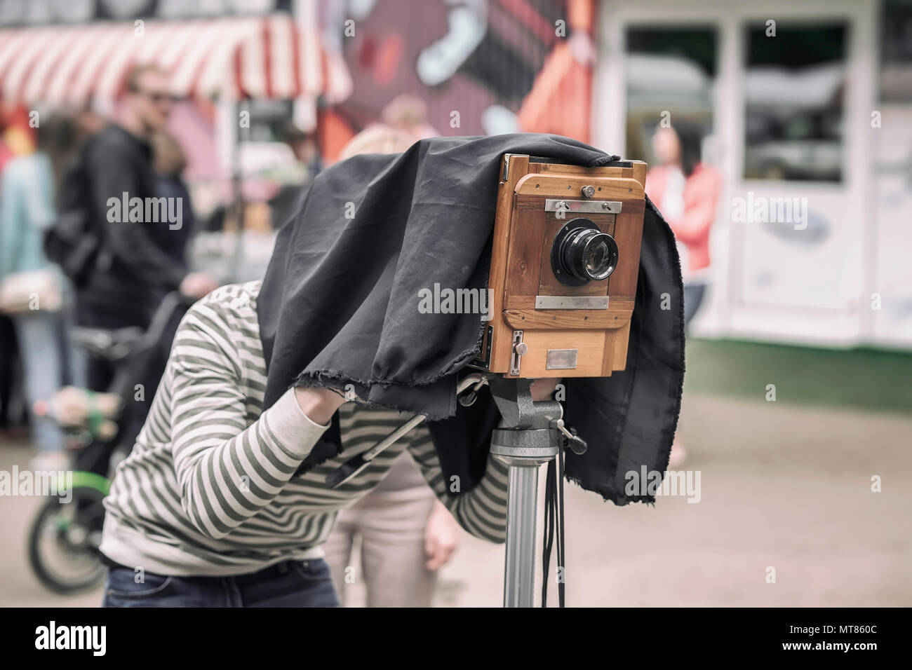 Fotograf mit Vintage Holz- Kamera unter dunklen Stoff Cape, fotografieren Kunden, Artefakt, Altertum, Rarität Konzept Stockfoto