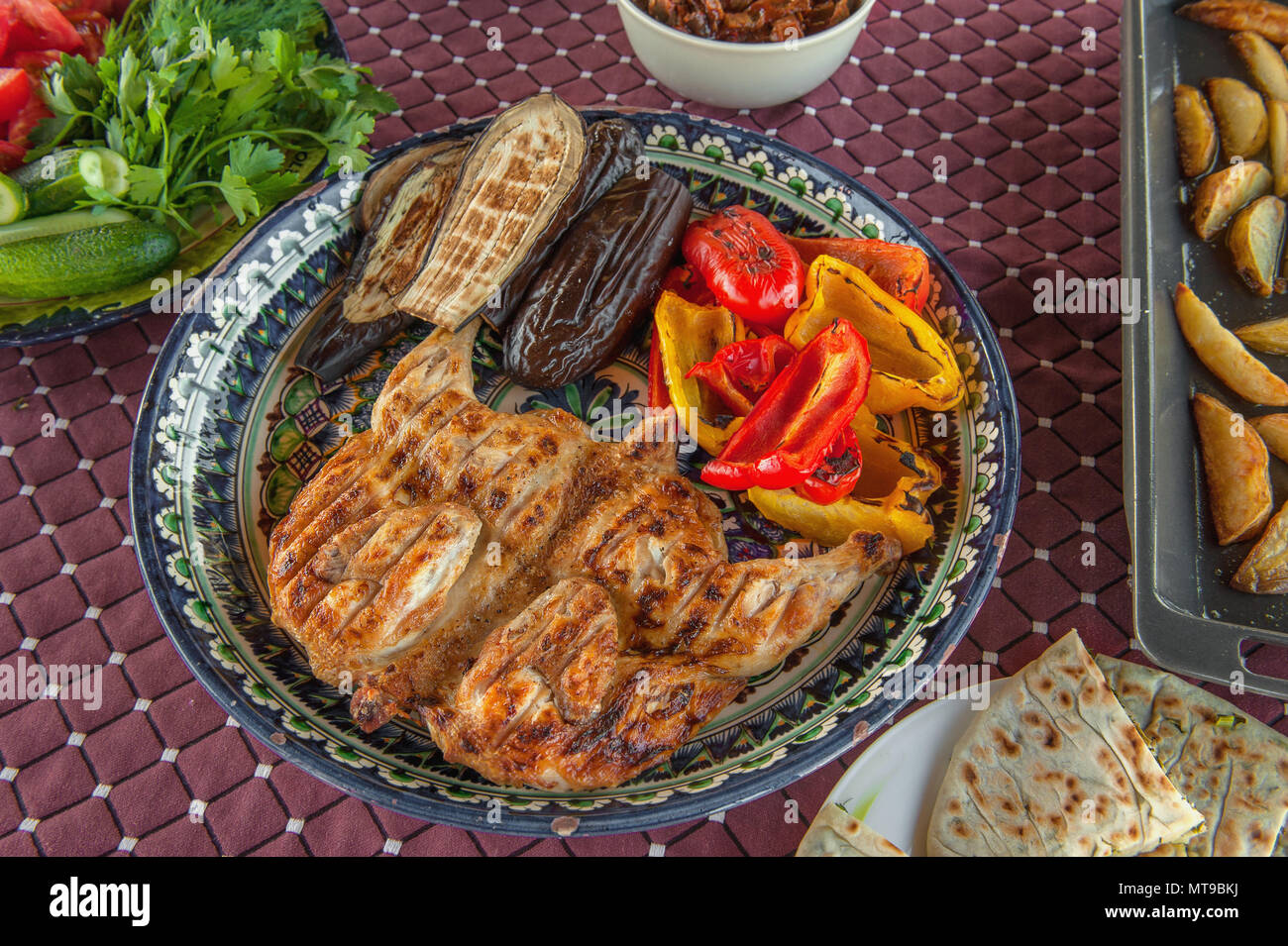 Gegrillte Tabak Huhn mit Sauce auf einer Steinplatte mit Bulgarischen gebratene Paprika aubergine Zucchini und Knoblauch. Natürliche hausgemachte Speisen Stockfoto