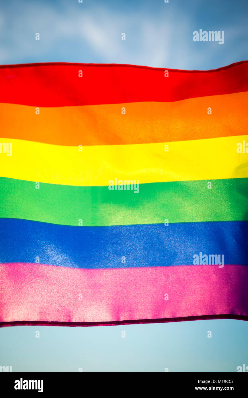 Regenbogen Fahnen fliegen in der hellen Sonne am Rande eines bunten Sommer Gay Pride Parade Stockfoto