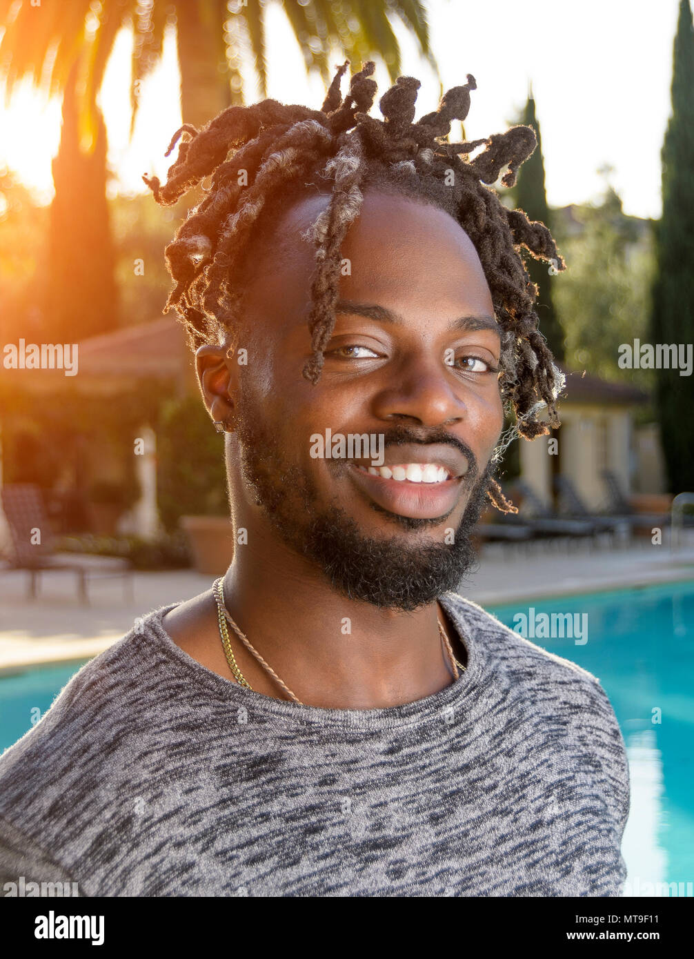 Porträt von einem gutaussehenden jungen afrikanischen amerikanischen Mann lächelnd Gegenlicht der Sonne. Stockfoto