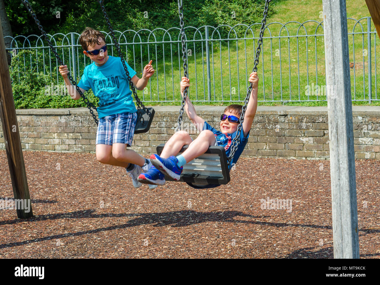 Junge Brüder spielen auf Schaukeln auf dem Spielplatz in der Junggesellen Morgen in Windsor, UK. Stockfoto