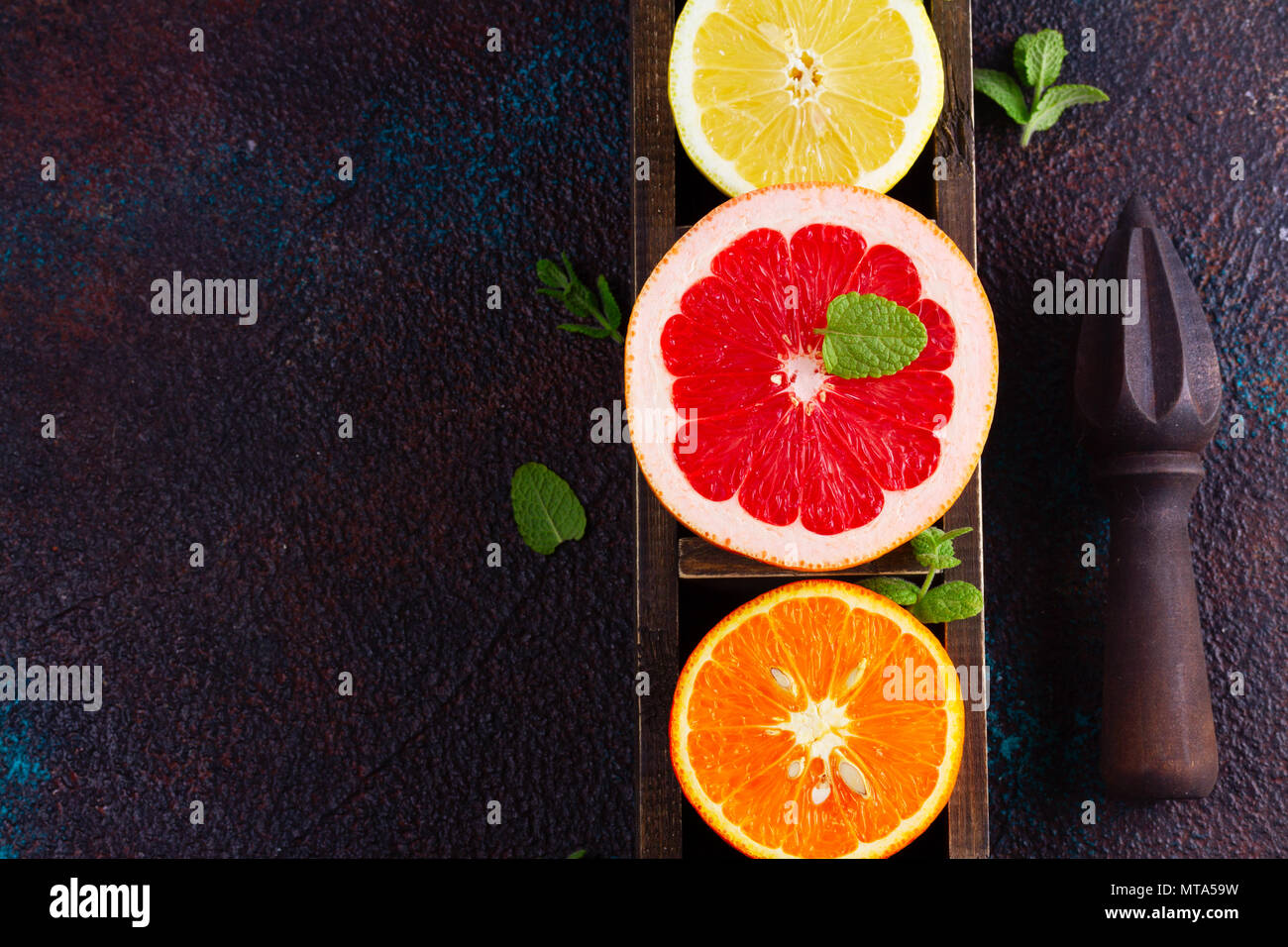 Orange, Zitrone und Grapefruit bunte Scheiben mit Zitrusfrüchten Reibahle auf dunklem Hintergrund, Falt legen Szene Stockfoto