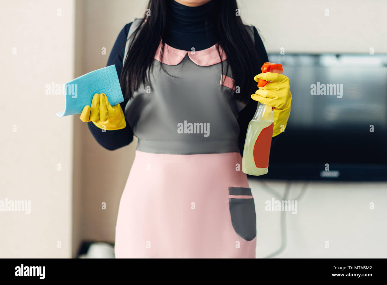 Weibliche cleaner in Uniform und Handschuhe hält Reinigungsgeräte in Händen, hotel zimmer einrichtung. Professionelle allgemeine Ordnung und Sauberkeit, die Putzfrau Stockfoto