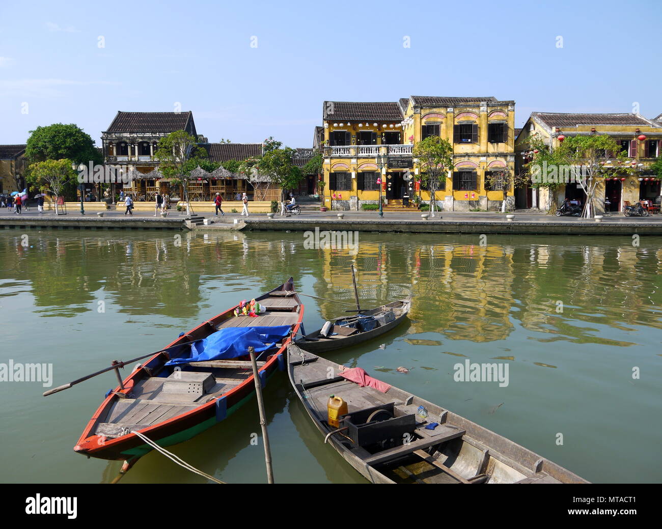 HOI AN, VIETNAM - 19. MÄRZ 2018: Schönen Tag in Hoi An Altstadt mit Blick auf die traditionellen Boote, gelbe Häuser am Ufer des Flusses, und die Touristen Stockfoto