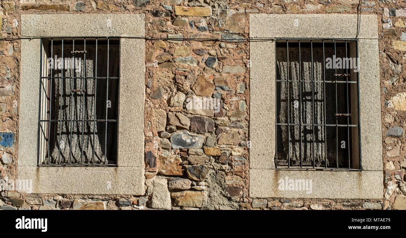 Zwei Fenster mit Granit Rahmen und Espartogras Jalousien im historischen Viertel von Caceres, Spanien Stockfoto
