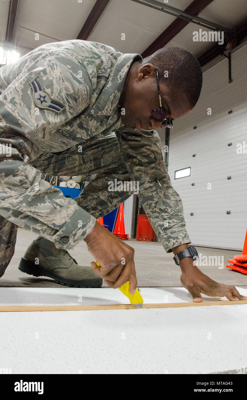 Airman 1st Class Marzell Charles, 108 Tiefbau Squadron Strukturen Shop, schneidet eine Decke Fliesen zu Größe, bei Joint Base Mc Guire-Dix - Lakehurst, New Jersey, 19. April 2017. Charles wird der neu schneiden Deckenfliese mit einem Tile durch ein kürzlich Feste undichten Leitung Vorrichtung beschädigt wurde, zu ersetzen. Stockfoto