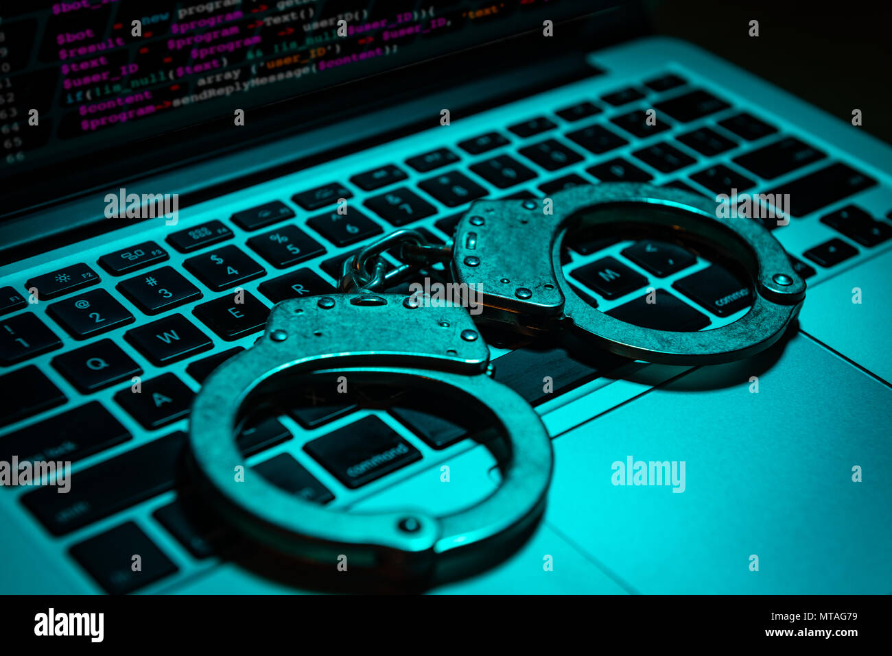Ein paar Handschellen sitzen auf einem Laptop Tastatur. Technologie/Internetkriminalität Konzept. Stockfoto