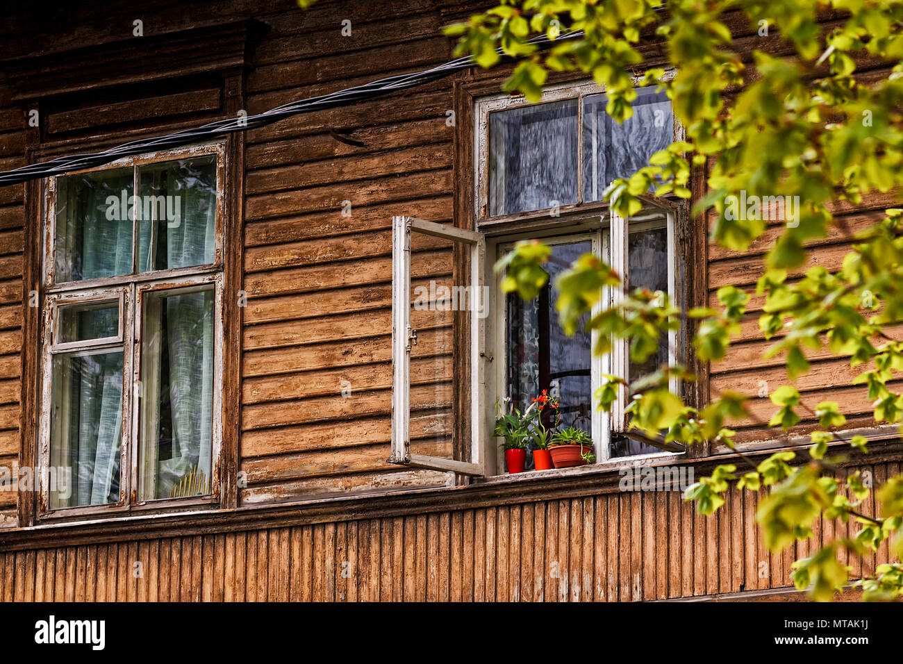 Drei rote Blumentöpfe stehen auf einem offenen Fenster eines alten Holzhaus.  Das Haus ist in Tallinn, Estland Stockfotografie - Alamy