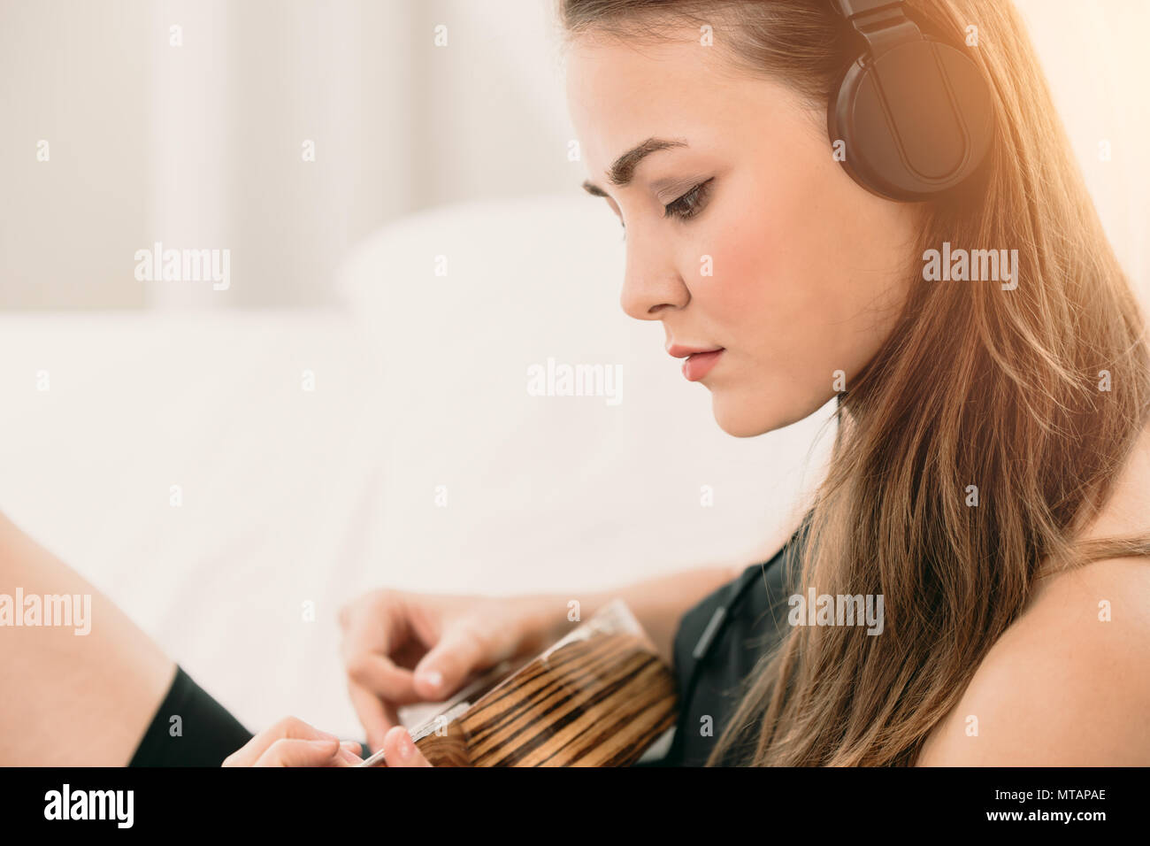 Frau Gitarre spielen und Musik hören wollen zu üben ihr Lied komponieren Stockfoto