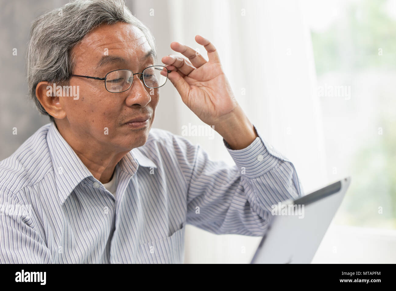 Asiatische Gläser älteren alten Mann glücklich mit Tablet Display für die Kommunikation mit anderen suchen. Stockfoto