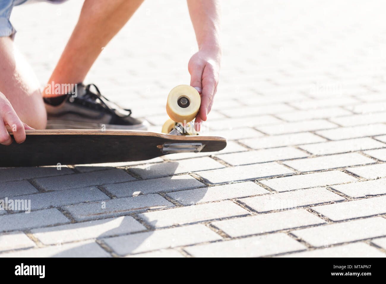 Skateboarder hält Rad der Skateboard, Prüfen und beheben Sie die Konzept Stockfoto