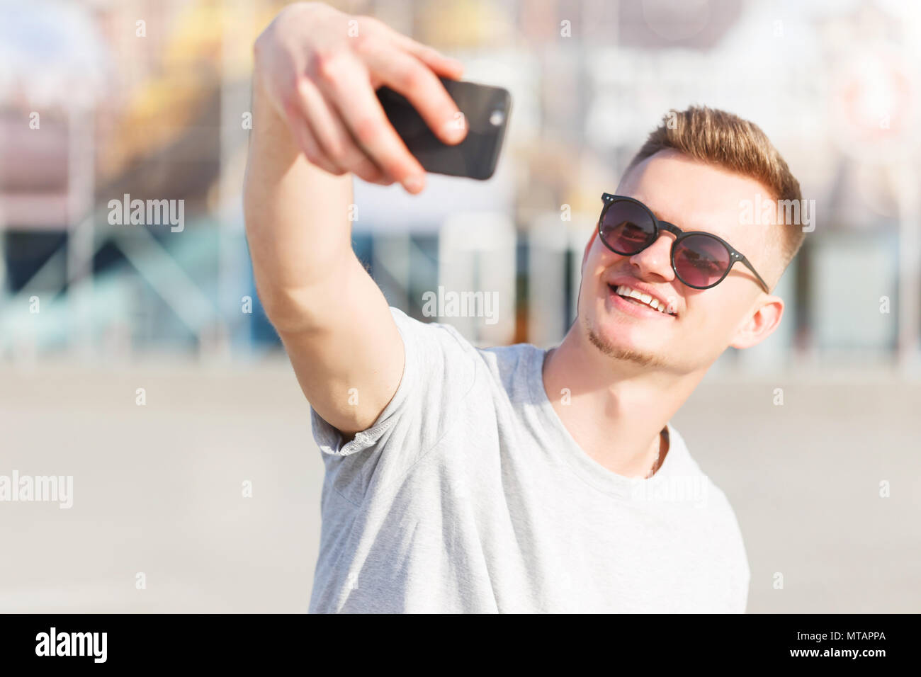 Skateboarder macht selfie vor modernen Gebäude im sonnigen Tag Stockfoto