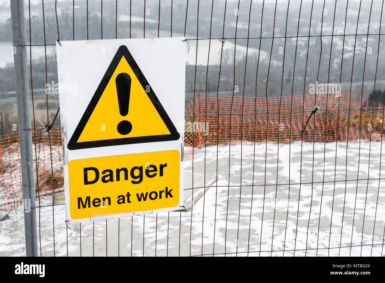 Gelb "Gesundheit und Sicherheit" Warnschild auf einer kleinen Baustelle - an einem verschneiten Tag im Winter (ein paar Flecken im Bild). Stockfoto