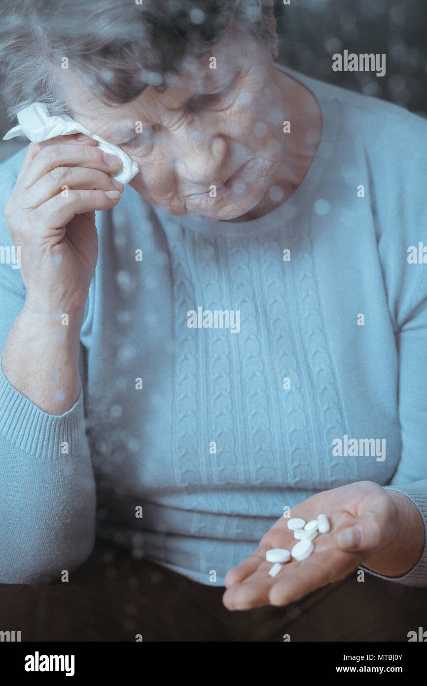 Kranke ältere Frau weinen, holding Pillen in der Hand Stockfoto