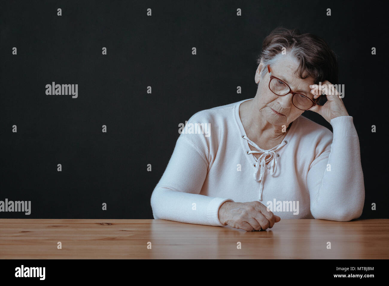 Traurig, einsam ältere Frau sitzt neben Tabelle Stockfoto