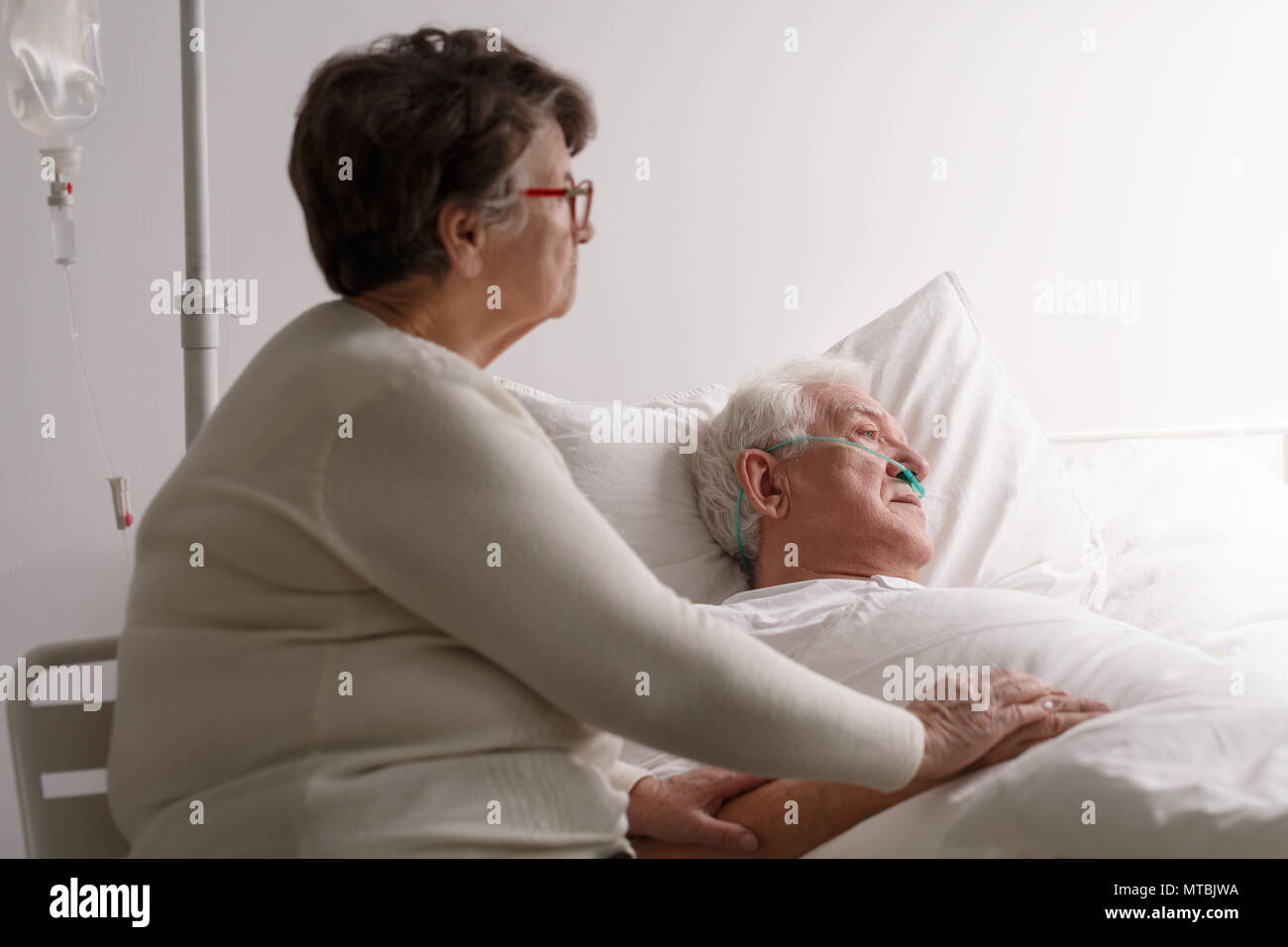 Traurige ältere Frau Unterstützung von Sterbenden kranken Mann im Krankenhaus bed Stockfoto