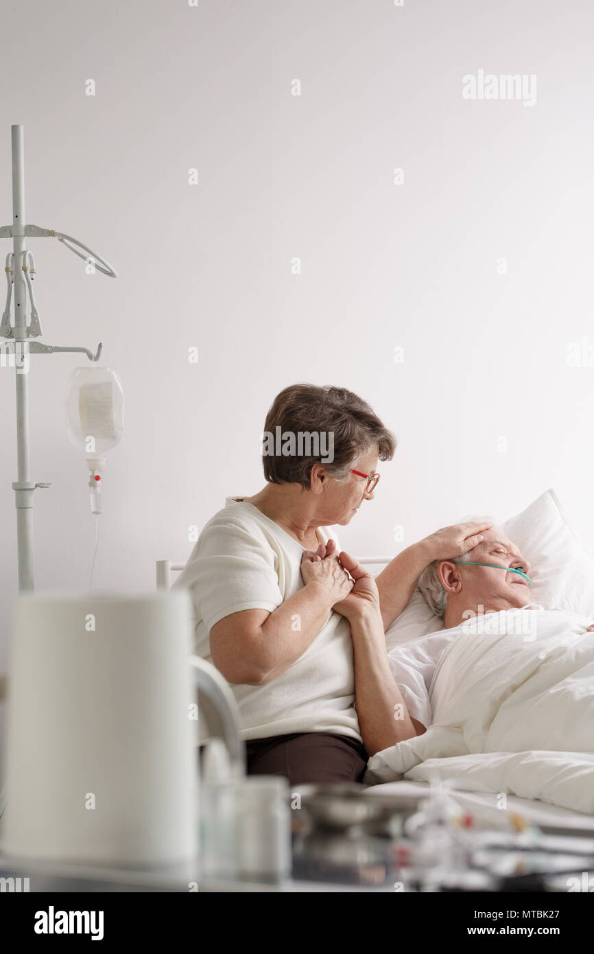 Ältere Frau die Hand der kranken sterbenden Ehemann im Krankenhaus Stockfoto
