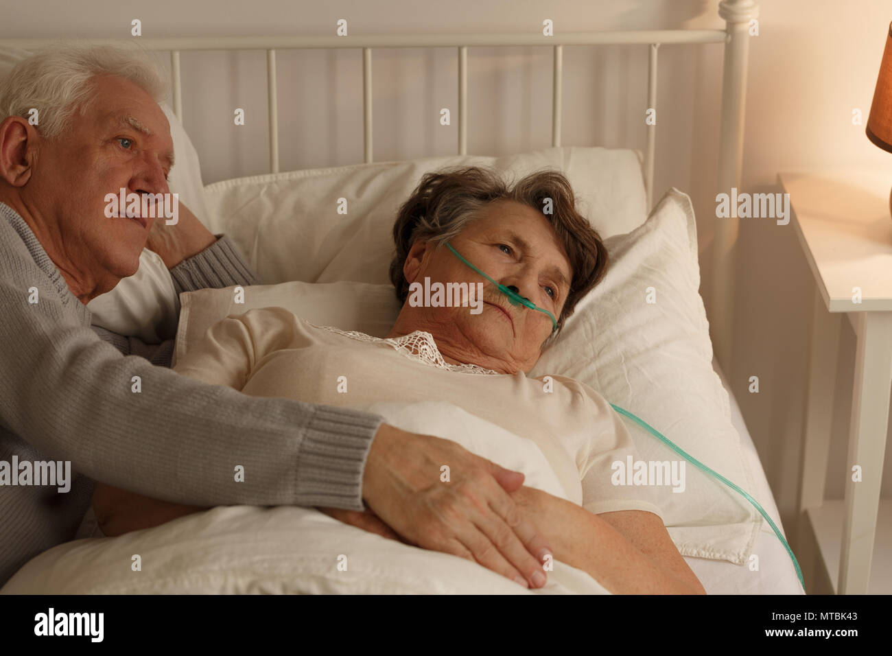 Mann liegend auf Bett neben älteren Menschen sterben kranke Frau Stockfoto