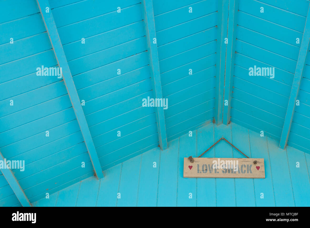 Love Shack in Hand gemalte Wörter auf einer hölzernen Tafel unter dem Dach einer Pastellfarben hellblau Blockhaus befestigt Stockfoto