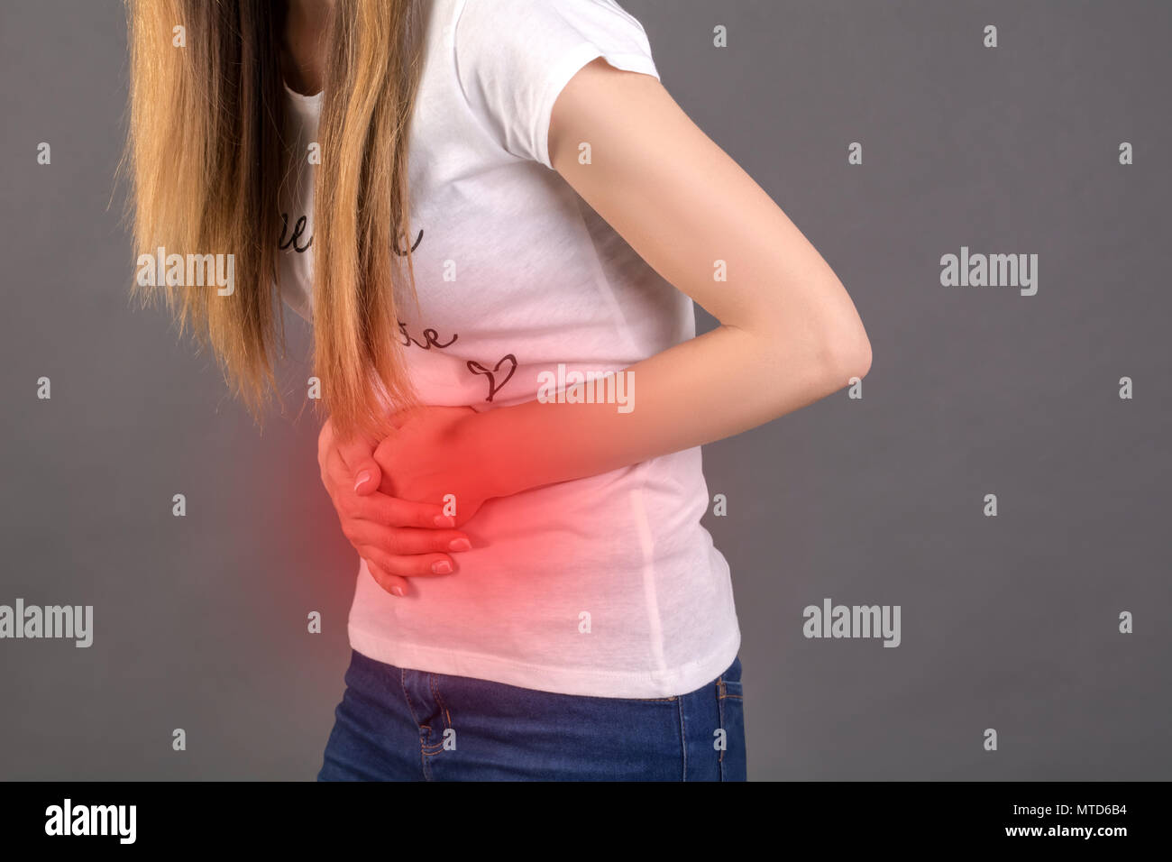 Schmerzen im Unterleib. Eine junge Frau hält ihre Hände auf ihrem Bauch Stockfoto