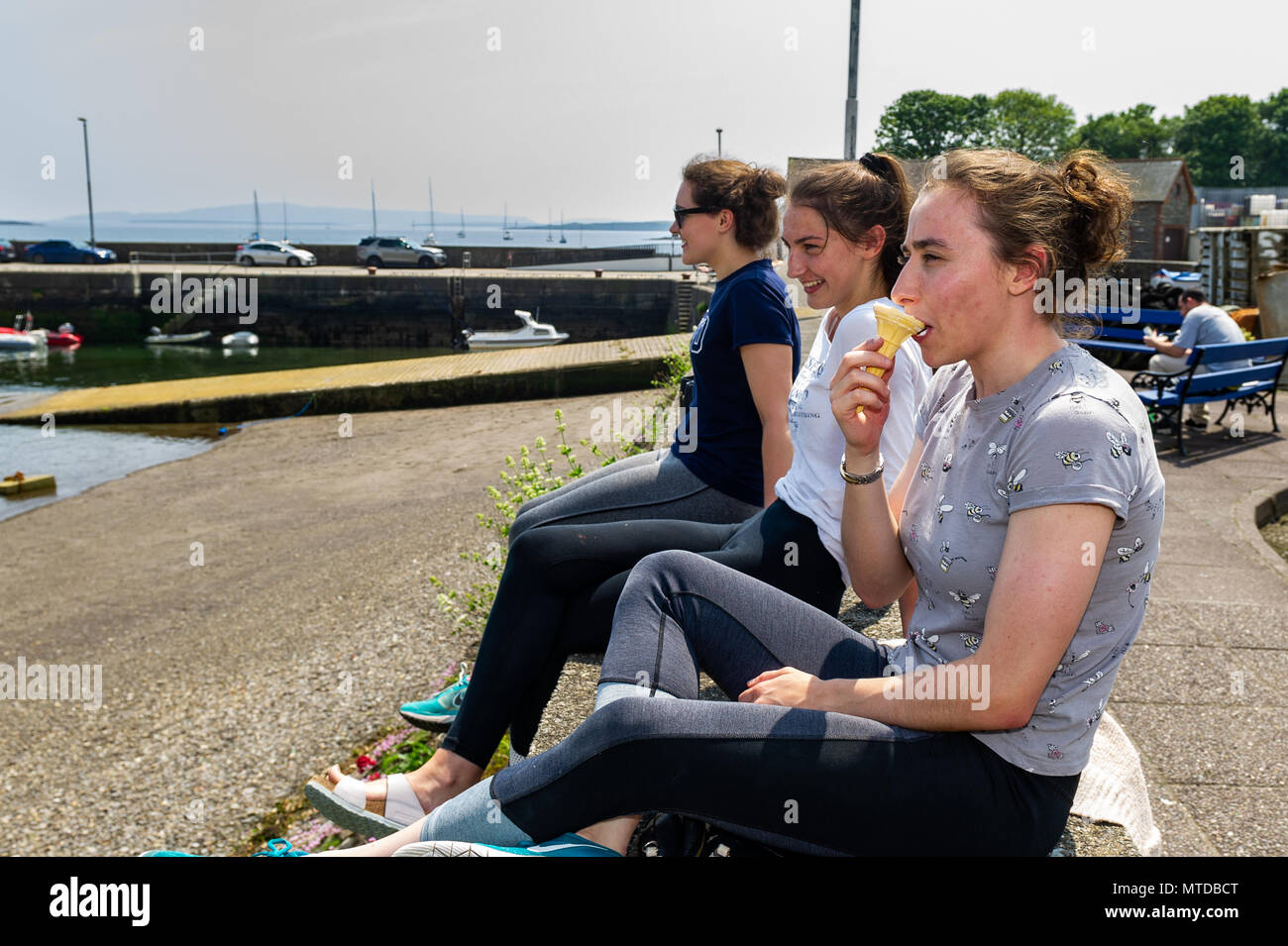Schull, Irland. Mai 2018. Am heißesten Tag des Jahres in West Cork genießen 3 junge Frauen ihre Mittagspause mit Blick auf den Hafen von Schull. Warme Sonnenstrahlen und Höhen von bis zu 27 C werden später am Tag schweren Schauern und möglichen Gewittern Platz machen. Quelle: AG News/Alamy Live News. Stockfoto