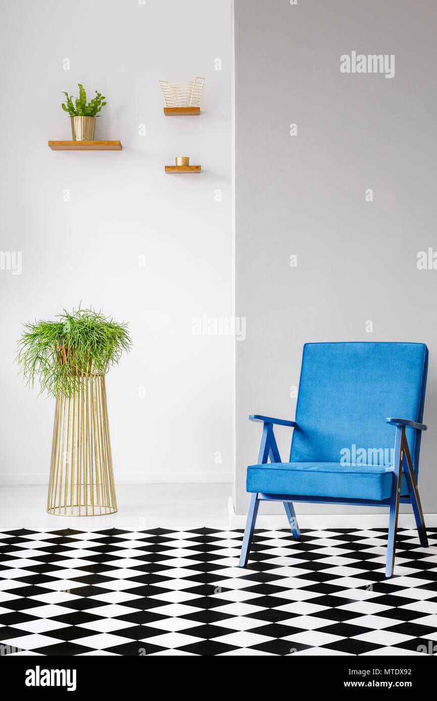 Real Photo eines blauen Sessel neben einer Anlage in einem weißen Wohnzimmer Einrichtung mit karierten Boden Stockfoto