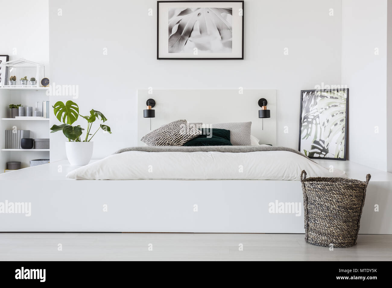 Warenkorb vor dem Bett auf der Plattform mit Pflanzen- und Poster in Weiß  Schlafzimmer Innenraum. Real Photo Stockfotografie - Alamy