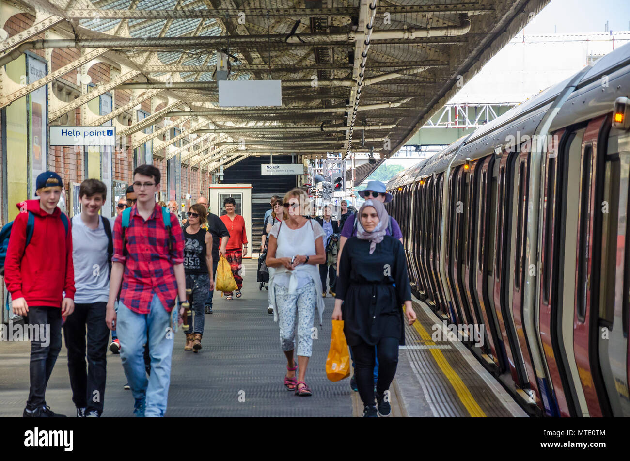 Passagiere Spaziergang entlang der Plattform in der Londoner U-Bahn-Station Hammersmith als ein Zug auf der Plattform wartet. Stockfoto