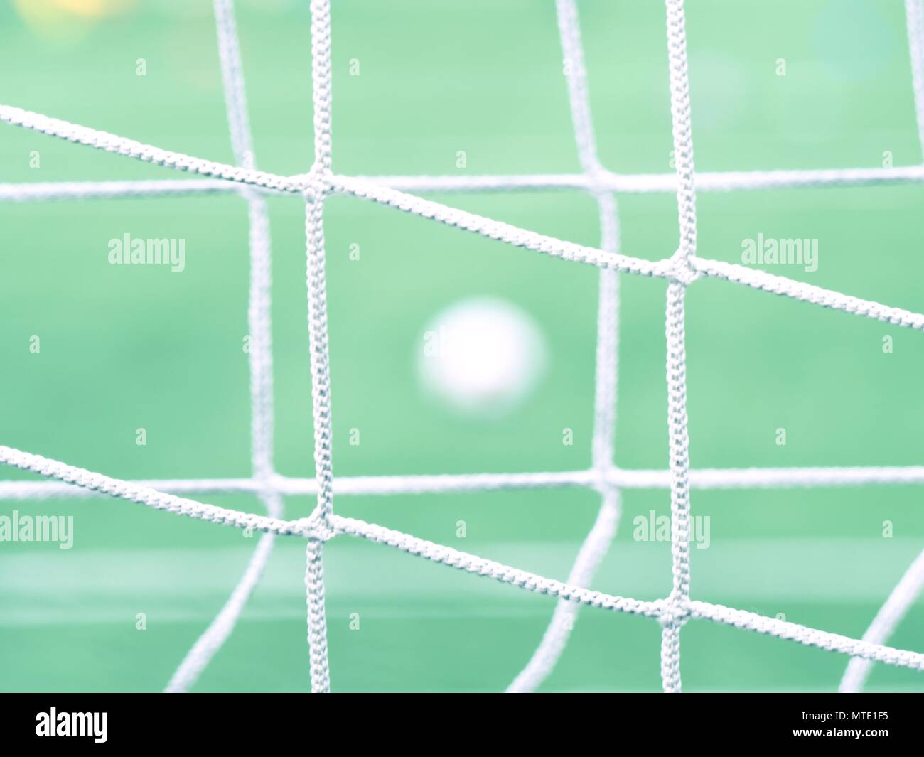 Die Fußball auf grünem Gras durch ein grünes Quadrat Tor net gesehen. Fußball-Ball im Ziel, sport Hintergrund Stockfoto