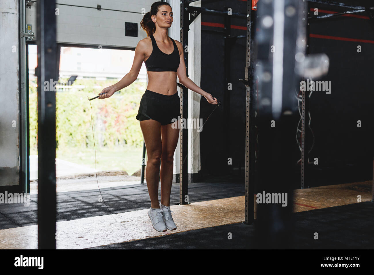 Sportliche Frau tun Fitness Training mit Seil springen in der Turnhalle Stockfoto