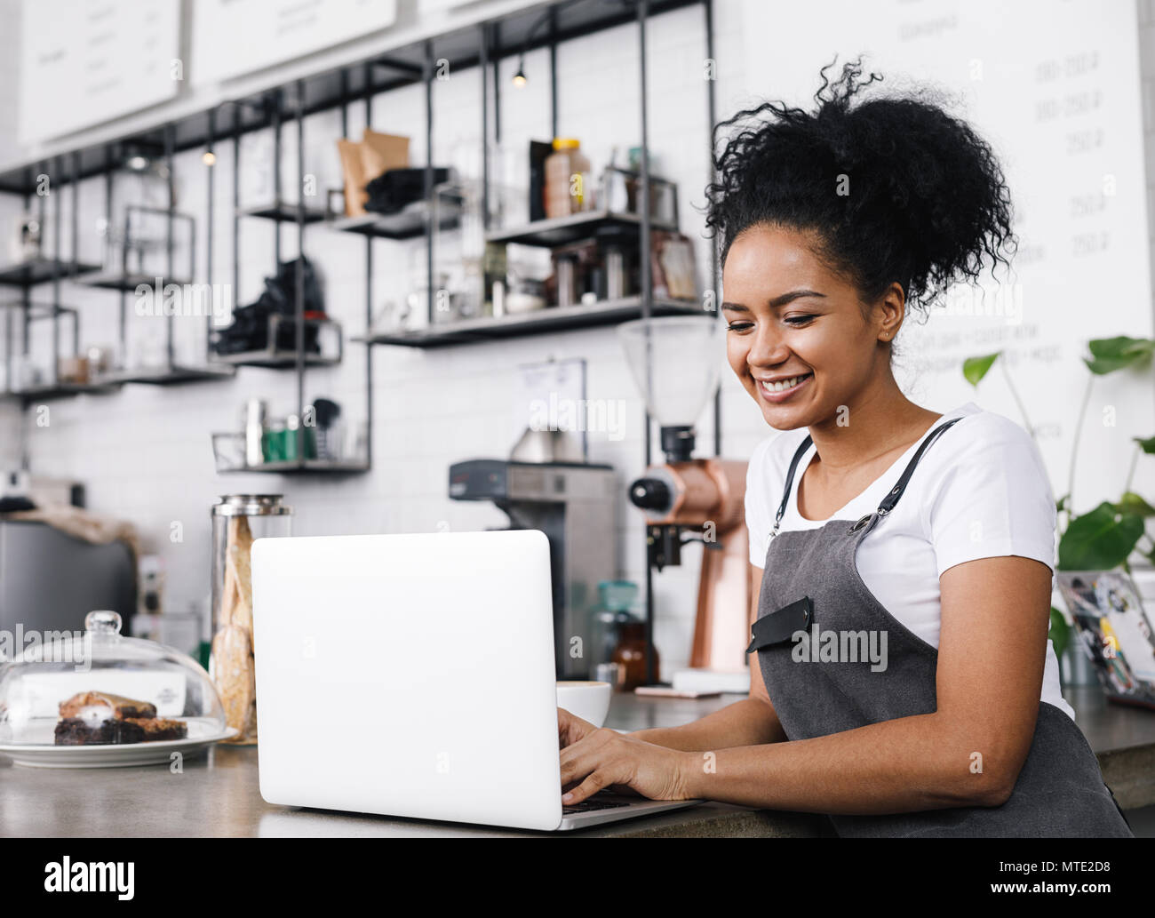 Junge cafe Besitzer arbeitet sie an ihrem Laptop, an der Theke stehend Stockfoto