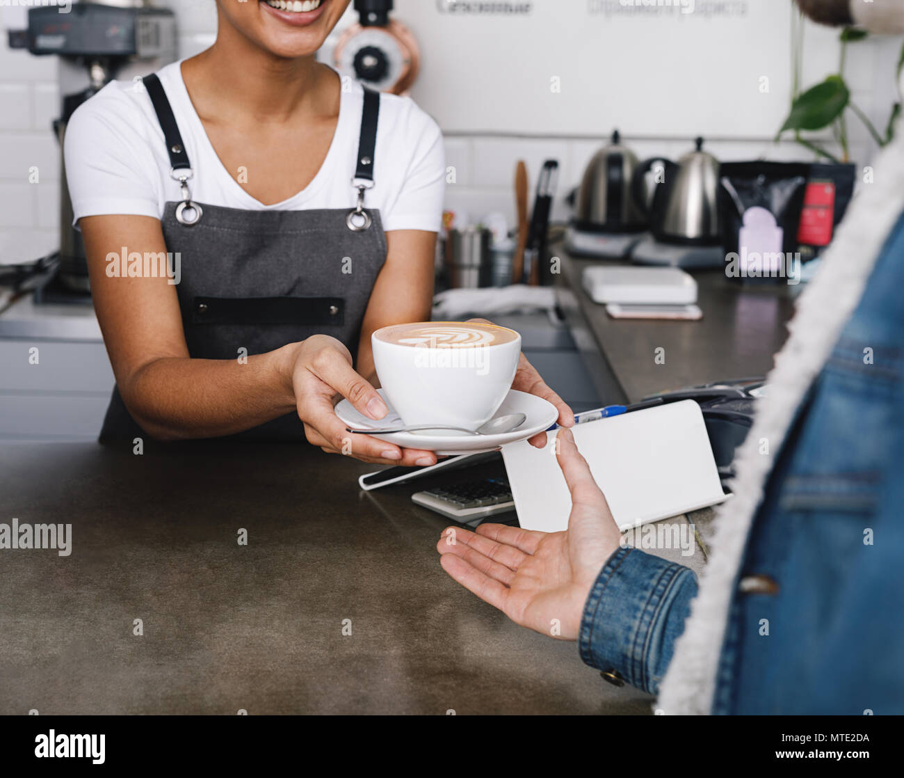 Nicht erkennbare Coffee Shop Besitzer übergeben, um eine Tasse Kaffee zu Ihren Kunden Stockfoto