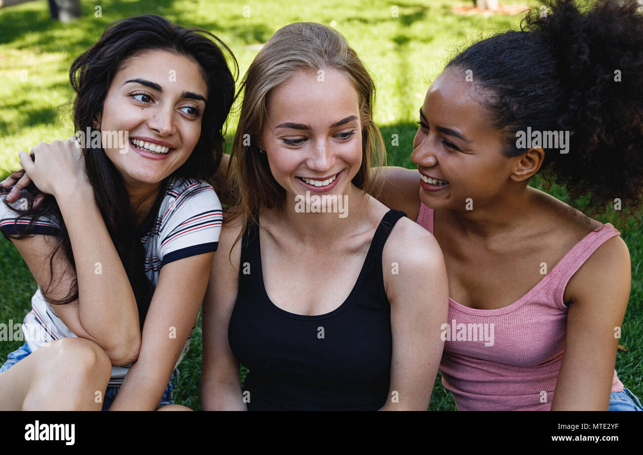 Drei junge Frauen in einem Park sitzend, in guten Zeiten Stockfoto