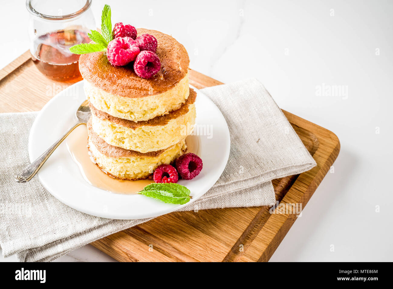 Trendige asiatische Lebensmittel, flauschige Japan souffle Pfannkuchen, Hotcakes mit Ahornsirup und Himbeere Licht konkreten Hintergrund Kopie Raum Stockfoto