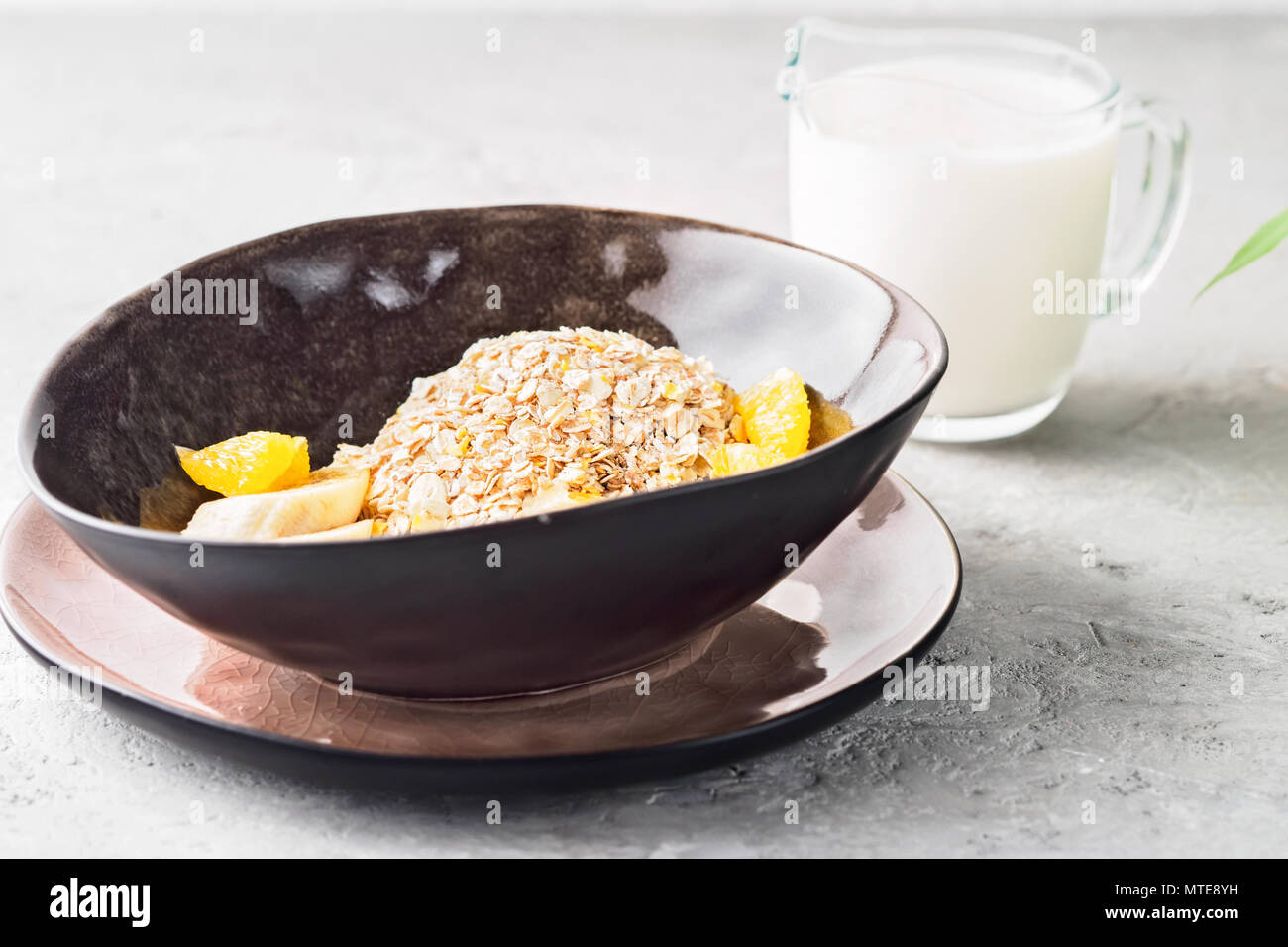 Hafer Gerste Weizen Roggen Mais mix Flocke richtige Ernährung Ernährung mit Stücken Banane orange und Glas Milch Stockfoto