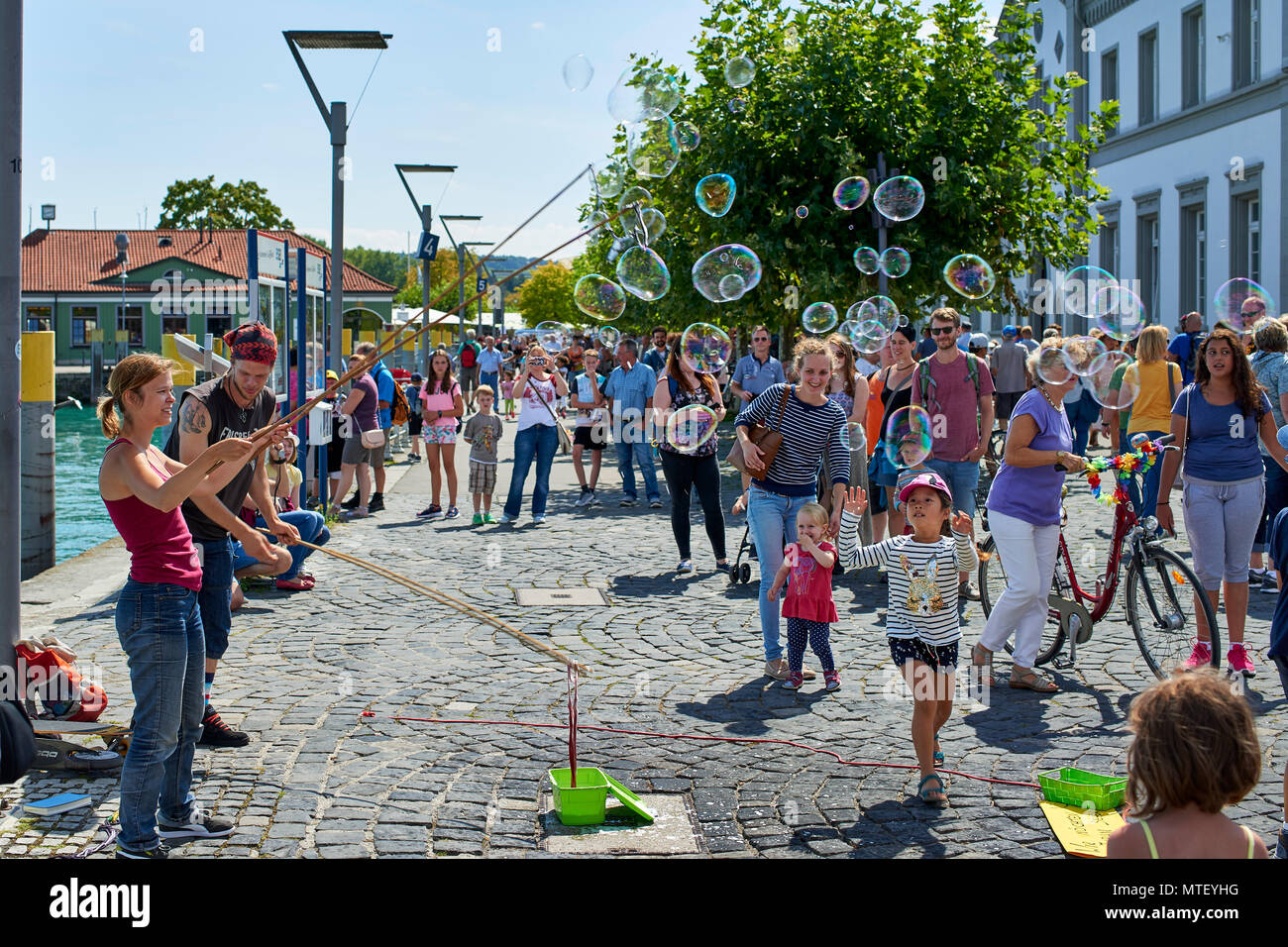 Paar Animateure unterhalten die Kinder und öffentliche Seifenblasen auf dem Platz in Konstanz Stockfoto
