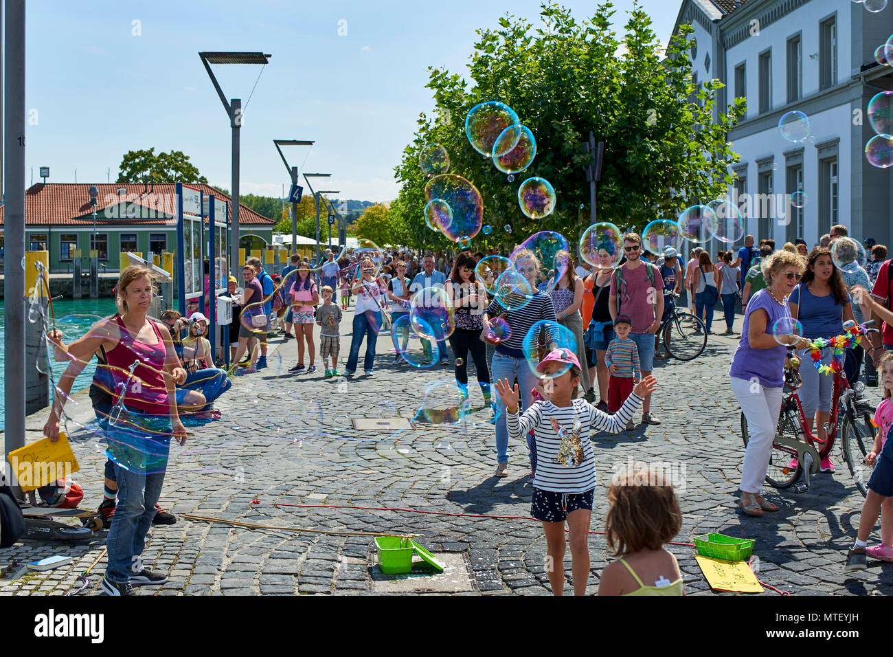 Paar Animateure unterhalten die Kinder und öffentliche Seifenblasen auf dem Platz in Konstanz Stockfoto