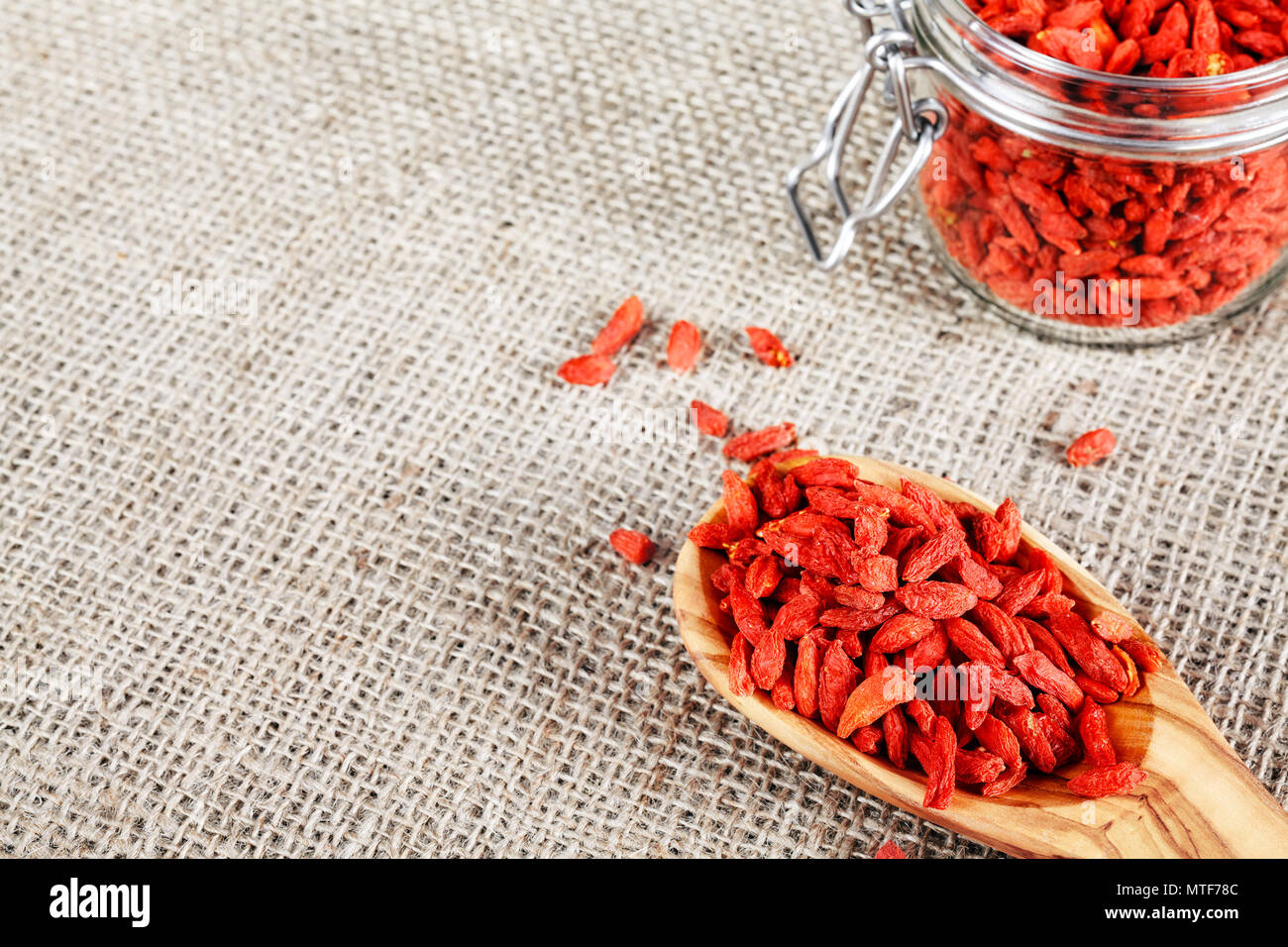 Getrocknete Goji Beeren auf einem Löffel aus Holz und Glas auf Leinen Hintergrund, selektive konzentrieren. Stockfoto