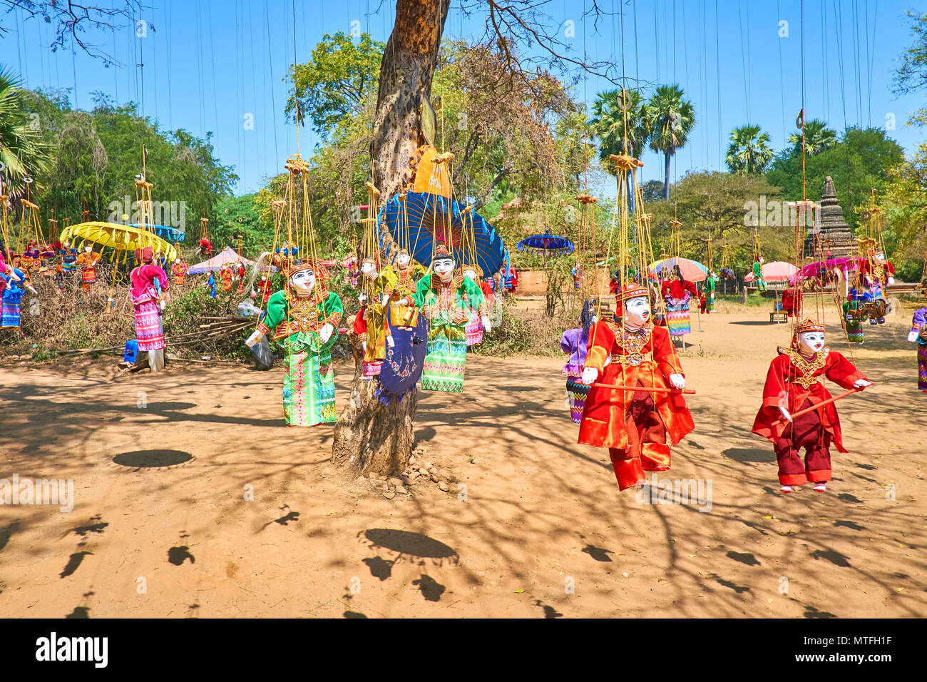 Traditionelle Handarbeit string Marionetten in bunten Kleidern und helle Schirme hängen am Baum und flattern im Wind in archäologische Stätte von alten Beutel Stockfoto