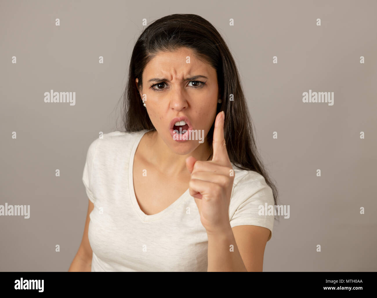 Nahaufnahme, Porträt einer attraktiven jungen Latin Frau mit einem wütenden Gesicht. Suchen wütend und verrückt, Zähne und der Zeigefinger in die Kamera. Hu Stockfoto