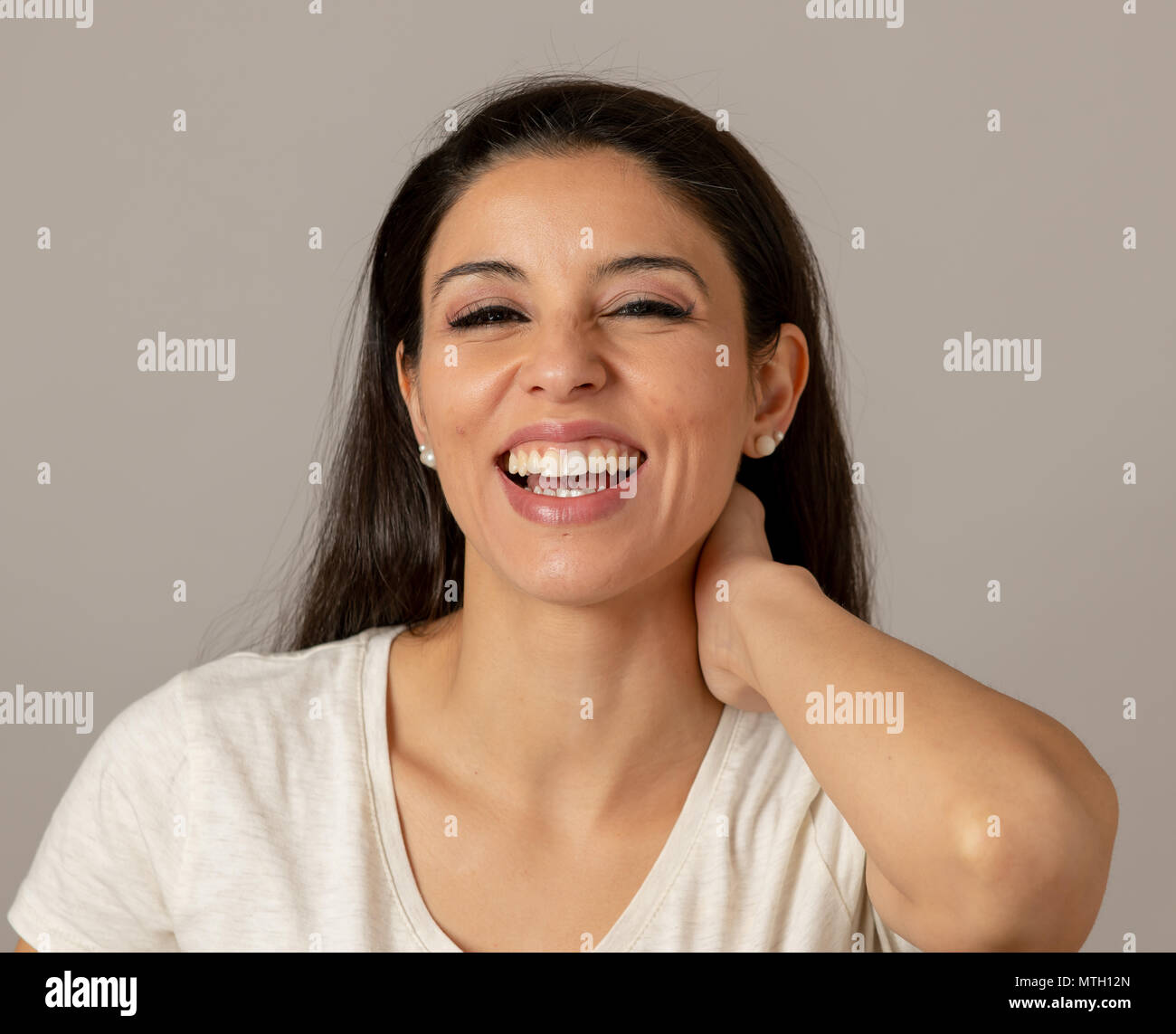 In der Nähe von schönen jungen latin Hispanic Frau fröhlich in die Kamera lachen. Glückliches Gesicht. Positive menschliche Mimik und Emotionen. Grau hinterg Stockfoto