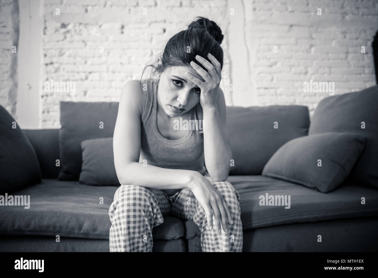 Schönen lateinischen gedrückt einsame Frau starrte traurig, Schmerzen, Trauer zu Hause auf Ihrem Sofa. Krise, Depression und psychische Gesundheit Konzept Stockfoto