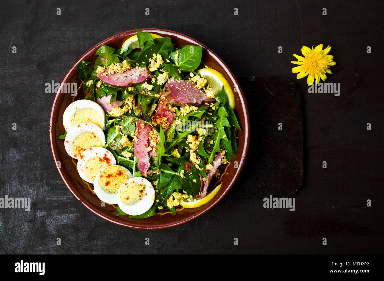 Löwenzahn Salat mit Eiern, Fleisch und Zitronensaft in eine Schüssel Draufsicht Stockfoto