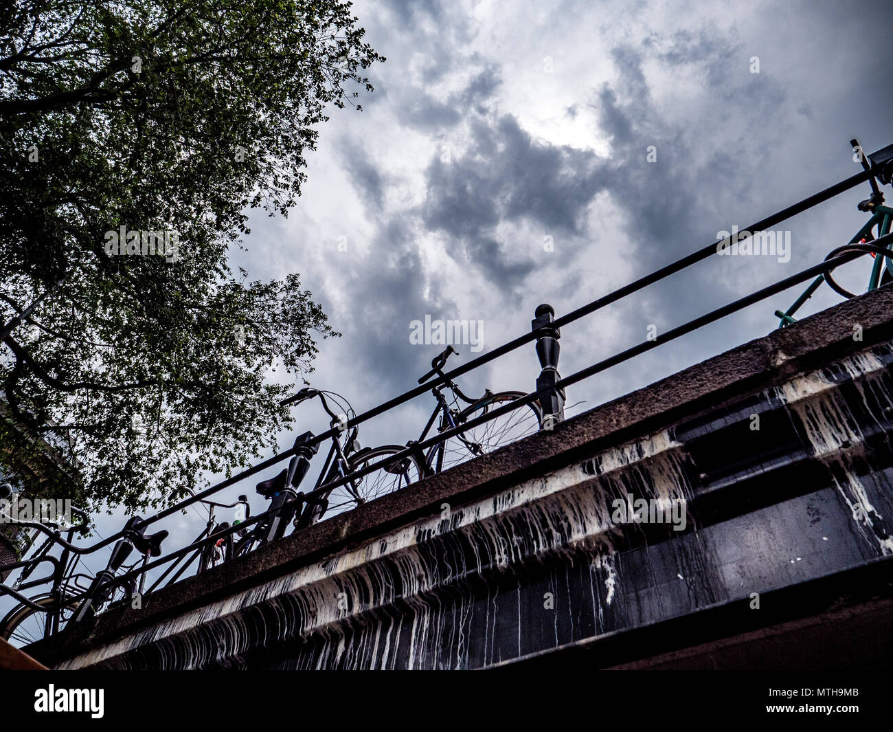 Fahrrad stehend auf einer Brücke von unten dramatische Wolken, Amsterdam Stockfoto