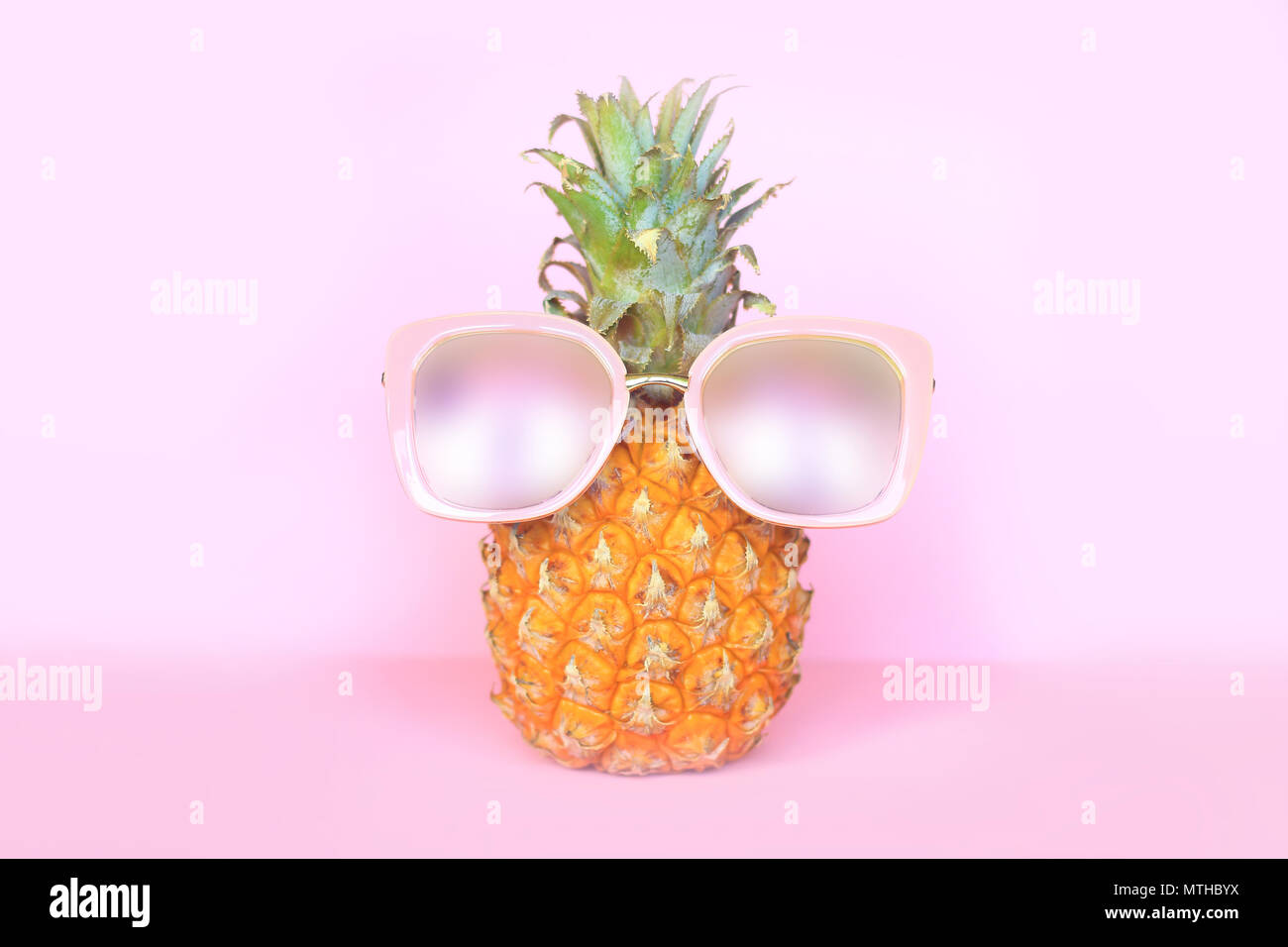 Saftige Ananas in Sonnenbrille auf rosa Hintergrund Stockfoto