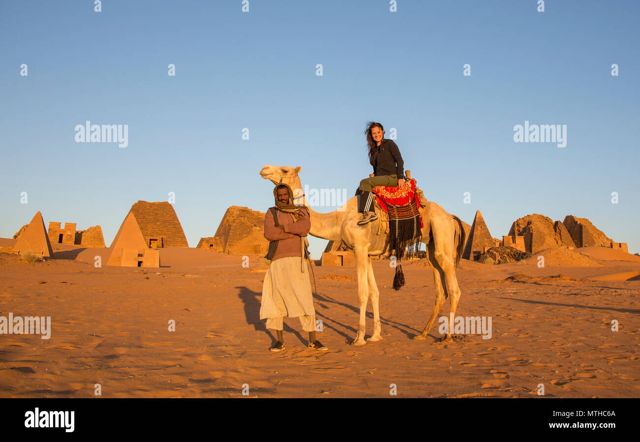 Meroe Pyramiden, Sudan - 19. Dezember 2015: eine Frau auf einem Kamel mit einem lokalen Mann vor der Pyramiden in der Wüste Stockfoto