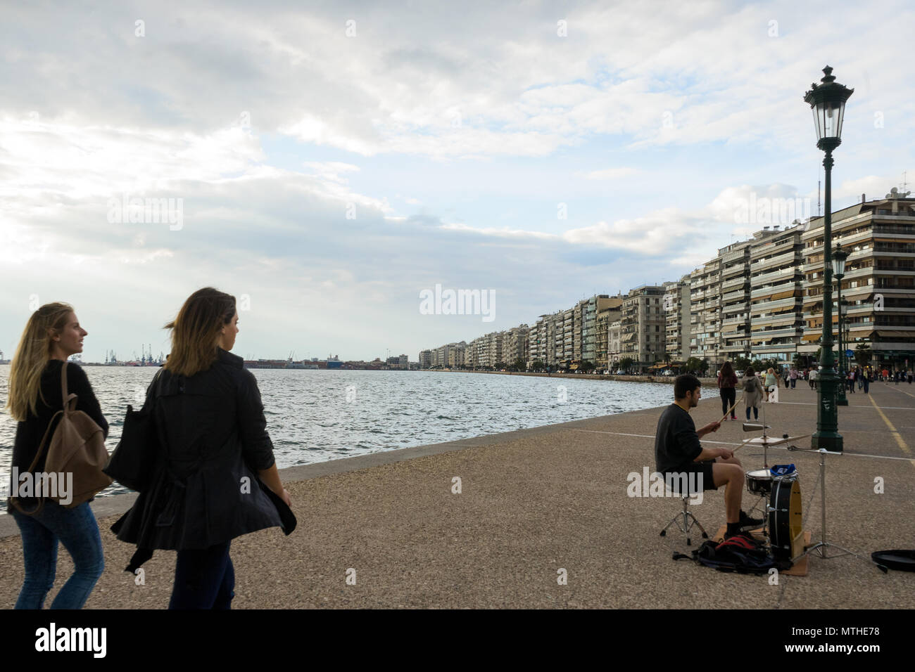 Thessaloniki, Griechenland, 29.09.2017: Ein paar Freundinnen gehen und ein Schlagzeuger spielt das Schlagzeug auf der Strandpromenade in Thessaloniki Stockfoto