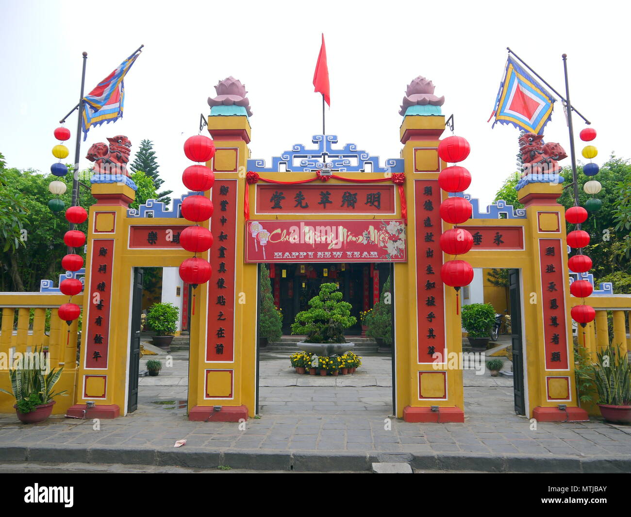 HOI AN, VIETNAM - 17. MÄRZ 2018: Das Tor des traditionellen Land Gottes Tempel mit Frohes neues Jahr unterzeichnen und bunte Fahnen in Hoi An, Vietnam Stockfoto