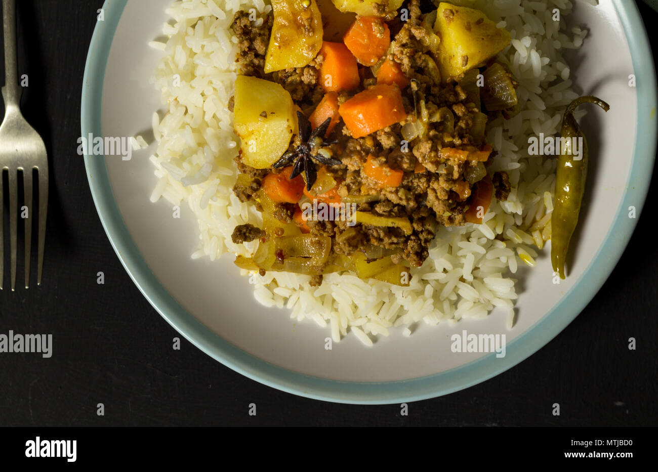 Curry Rindfleisch Karotten und Reis in der Platte mince, Ansicht von oben Foto auf Schwarz rustikalen Tisch Stockfoto